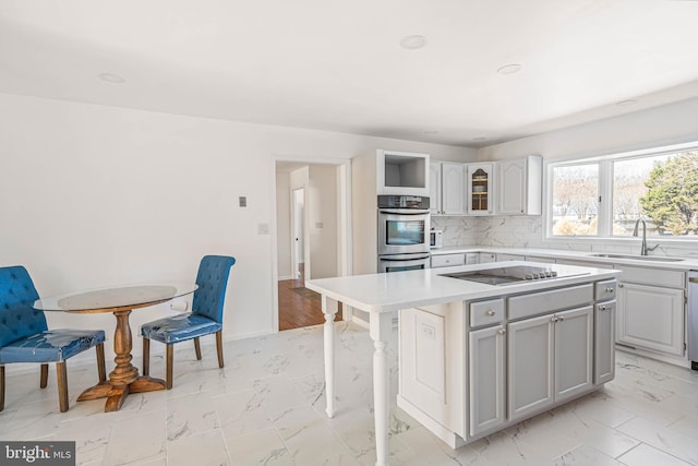 kitchen with marble finish floor, a sink, a kitchen island, double oven, and black electric stovetop