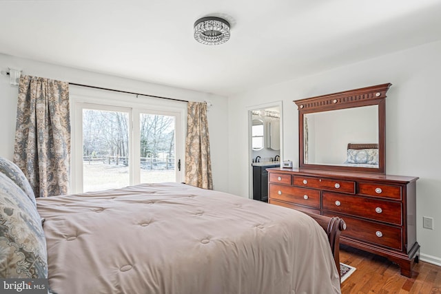 bedroom with baseboards, wood finished floors, access to exterior, and ensuite bathroom