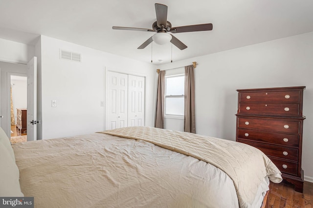 bedroom featuring dark wood-style floors, visible vents, ceiling fan, and a closet