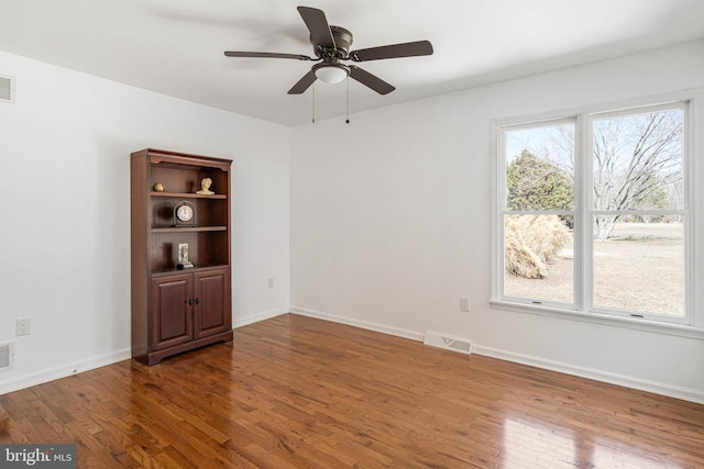 empty room with hardwood / wood-style flooring, baseboards, visible vents, and ceiling fan