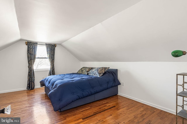 bedroom with hardwood / wood-style flooring, baseboards, and vaulted ceiling