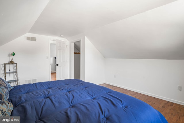 bedroom featuring visible vents, baseboards, wood finished floors, and vaulted ceiling