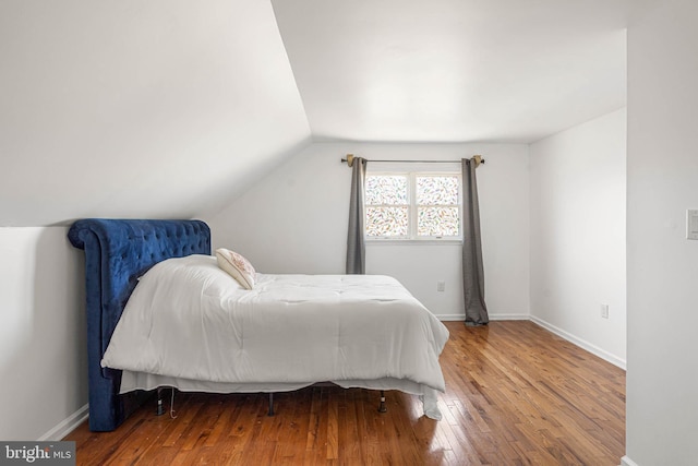 bedroom with hardwood / wood-style flooring, baseboards, and lofted ceiling