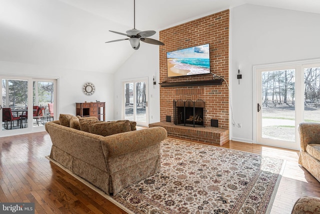 living room featuring hardwood / wood-style floors, a brick fireplace, high vaulted ceiling, and ceiling fan