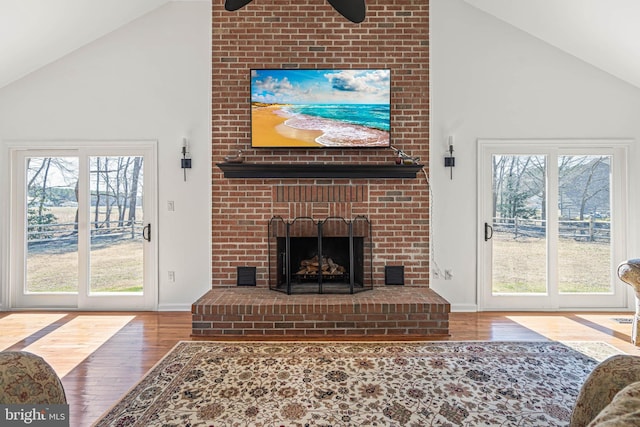 living area featuring plenty of natural light, a fireplace, high vaulted ceiling, and wood finished floors