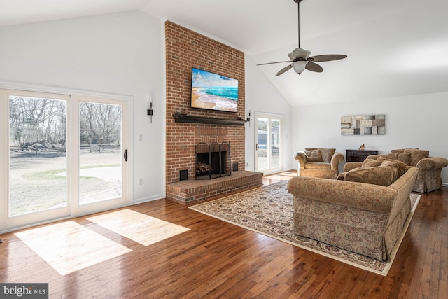 living area with a ceiling fan, dark wood-style floors, a fireplace, and high vaulted ceiling