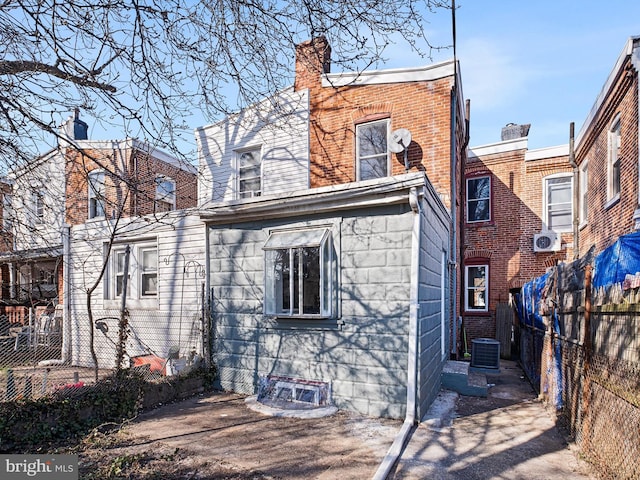 back of property featuring brick siding, a chimney, and fence