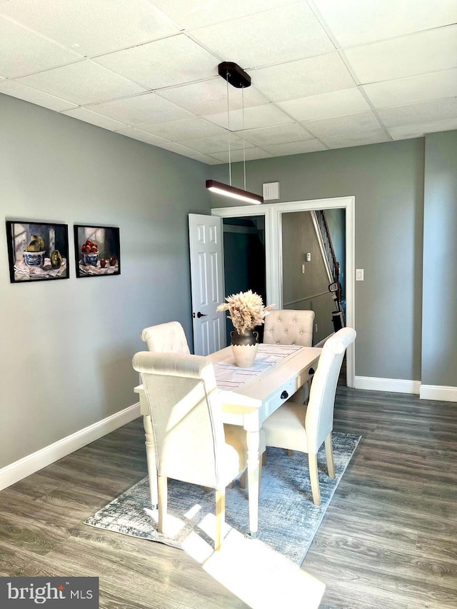 dining room with baseboards, a paneled ceiling, and wood finished floors