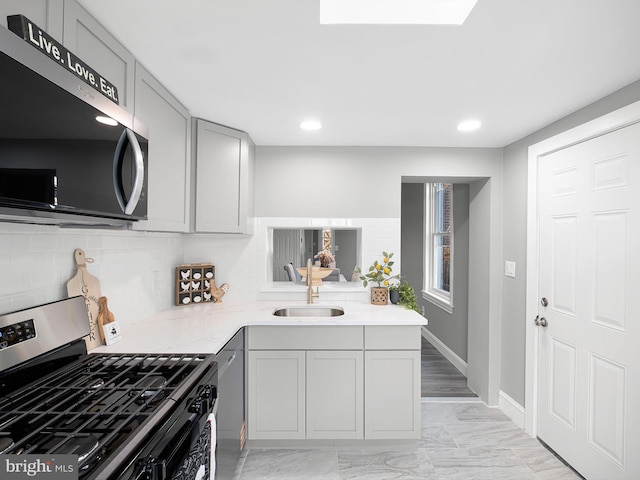 kitchen with baseboards, a sink, decorative backsplash, appliances with stainless steel finishes, and marble finish floor