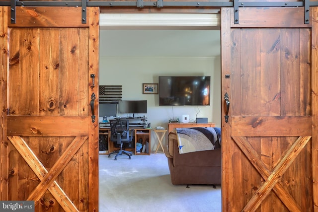 home office with a barn door and carpet floors