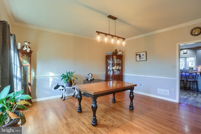 dining area with baseboards, wood finished floors, and crown molding