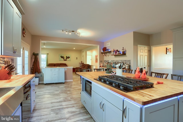 kitchen with black gas stovetop, open floor plan, and butcher block counters