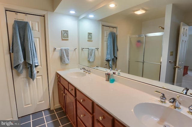 bathroom with tile patterned floors, a stall shower, double vanity, and a sink