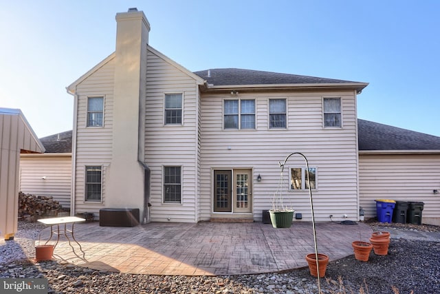 back of property featuring a patio, roof with shingles, and a chimney