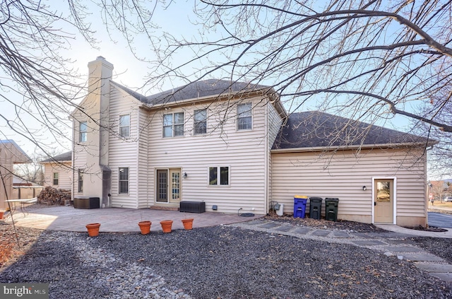 rear view of property with a patio area, central air condition unit, a chimney, and a shingled roof