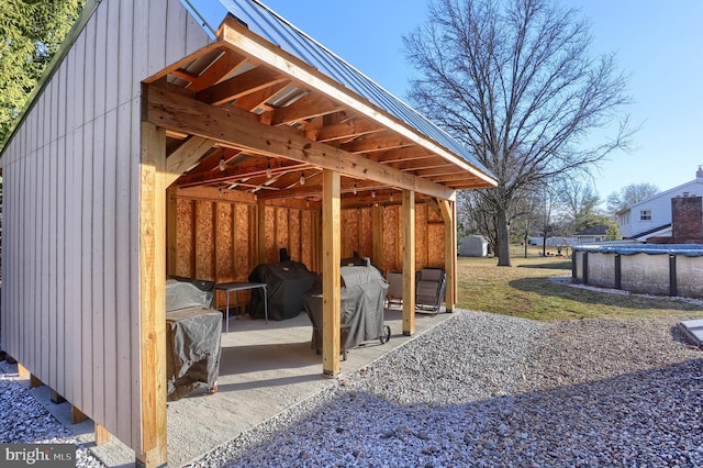 exterior space with a covered pool, an outbuilding, and a grill