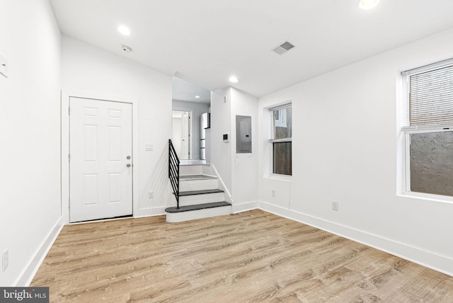 foyer entrance featuring electric panel, stairway, light wood-style flooring, and recessed lighting