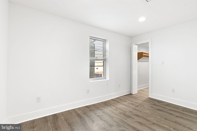 empty room with recessed lighting, baseboards, and wood finished floors