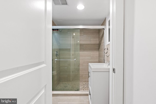 full bath featuring visible vents, vanity, and a shower stall