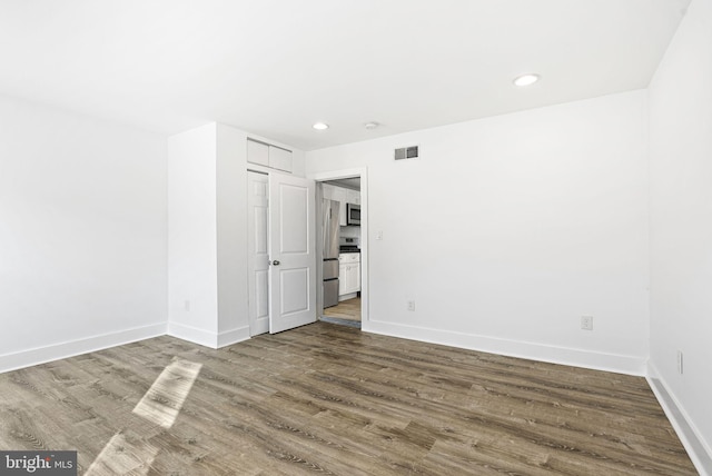 empty room featuring visible vents, baseboards, and wood finished floors