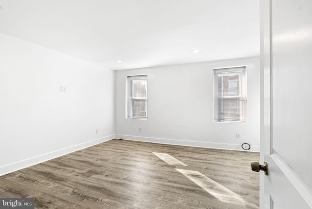 spare room featuring recessed lighting, baseboards, and wood finished floors