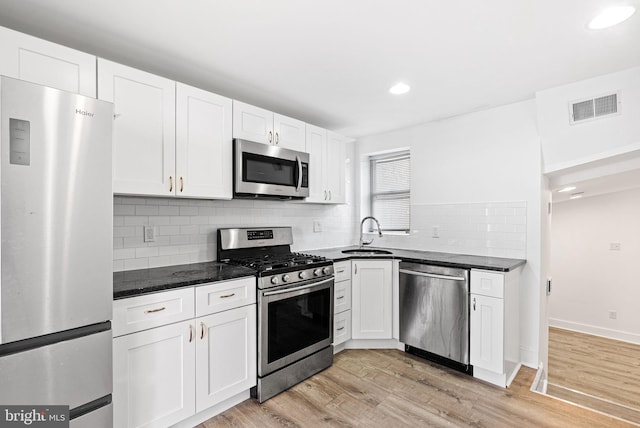 kitchen with visible vents, light wood-style flooring, a sink, white cabinetry, and stainless steel appliances