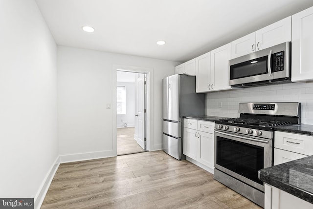 kitchen with backsplash, baseboards, appliances with stainless steel finishes, light wood-style floors, and white cabinets