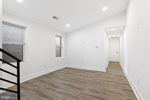 empty room with visible vents, recessed lighting, lofted ceiling, and wood finished floors