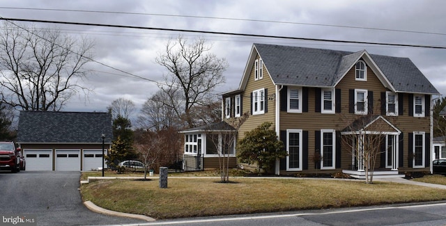 colonial house with a garage, roof with shingles, an outdoor structure, and a front yard