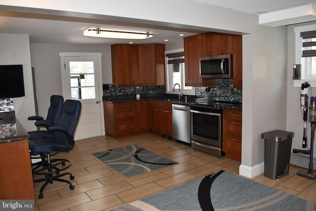 kitchen featuring wood tiled floor, a sink, appliances with stainless steel finishes, and tasteful backsplash