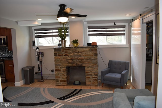 living room with a barn door, ceiling fan, baseboards, light wood-type flooring, and recessed lighting