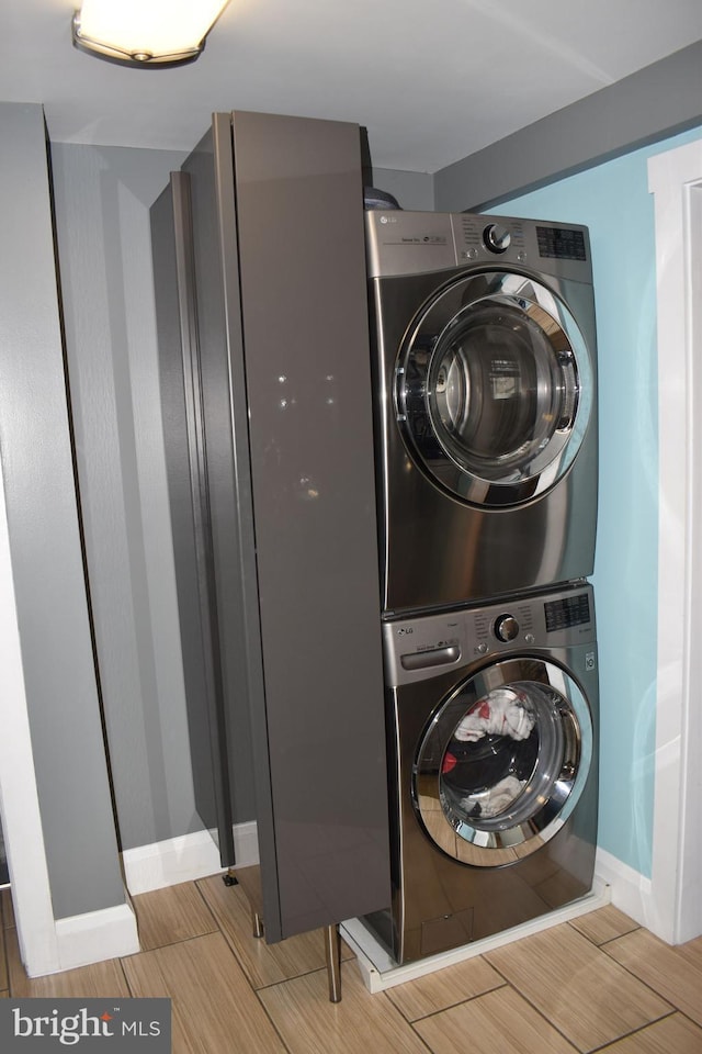 laundry room featuring baseboards, stacked washer and clothes dryer, and laundry area
