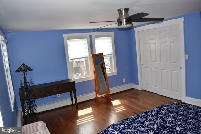 unfurnished bedroom with a baseboard radiator, ceiling fan, a closet, baseboards, and wood finished floors