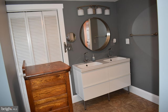 full bathroom with double vanity, tile patterned floors, baseboards, and a sink