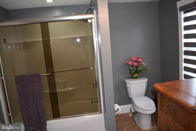 full bathroom featuring shower / bath combination with glass door, recessed lighting, toilet, stone finish floor, and baseboards