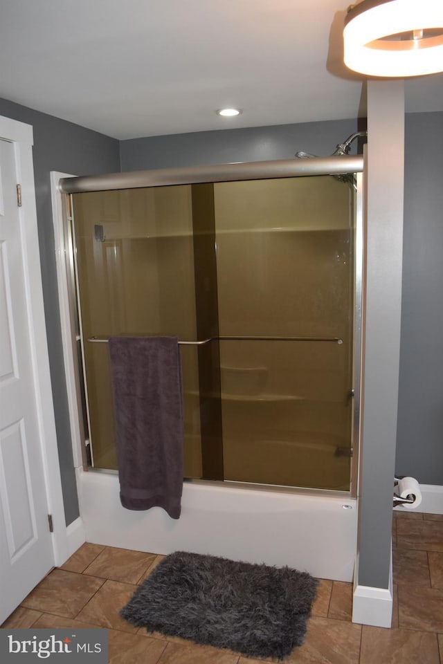 bathroom featuring shower / bath combination with glass door and baseboards