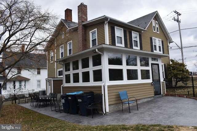 back of house featuring a patio area, a chimney, and fence