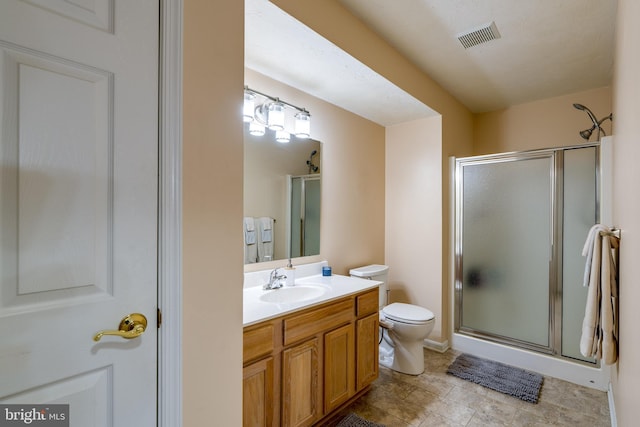 bathroom with vanity, a shower stall, toilet, and visible vents