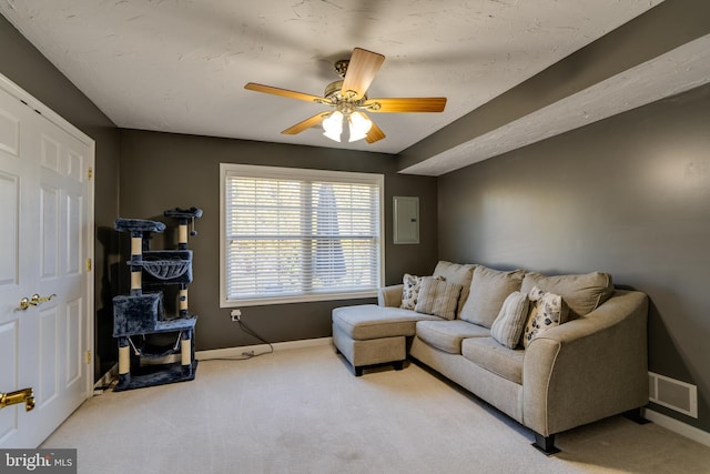 carpeted living room with electric panel, baseboards, visible vents, and ceiling fan