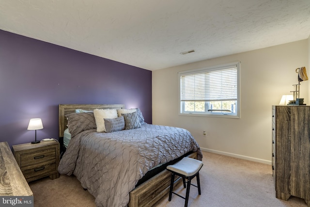 bedroom with baseboards, light carpet, a textured ceiling, and visible vents