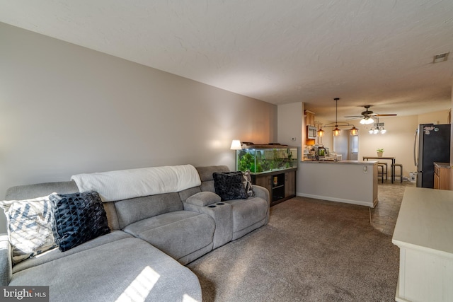 carpeted living area featuring baseboards, a ceiling fan, visible vents, and a textured ceiling