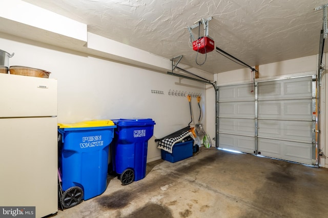 garage featuring a garage door opener and freestanding refrigerator