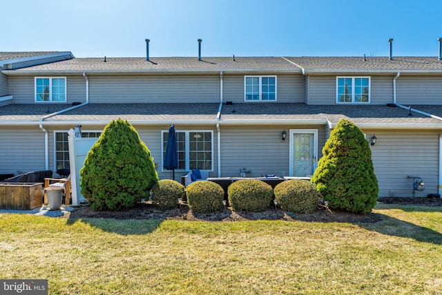 back of property with a lawn and a shingled roof