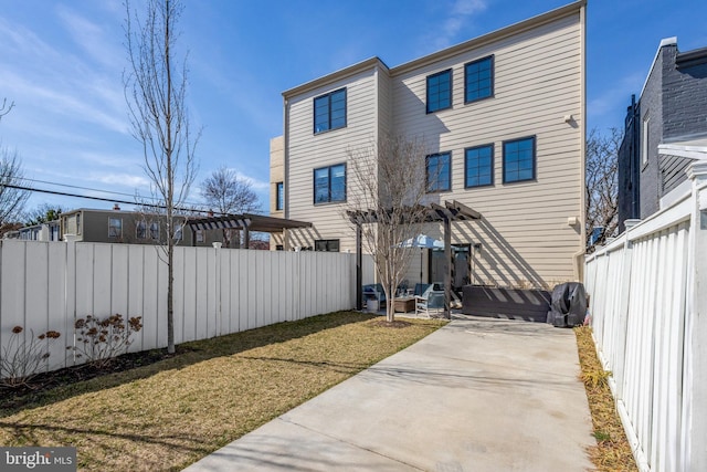 rear view of property featuring a yard, a patio, a pergola, and a fenced backyard