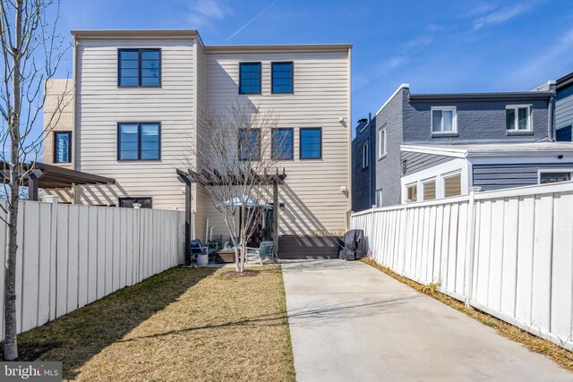 rear view of house featuring a patio area, a yard, and a fenced backyard