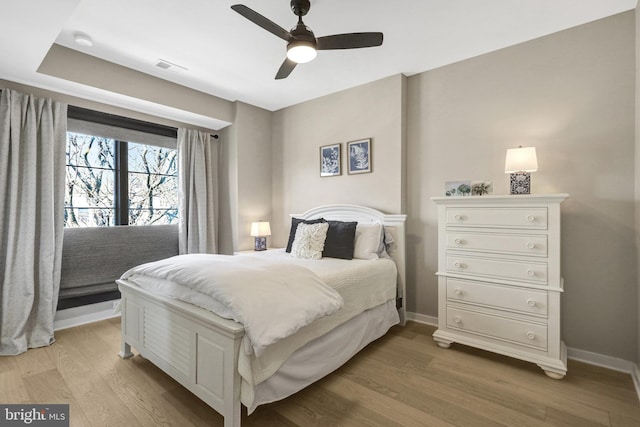 bedroom featuring a ceiling fan, visible vents, baseboards, and light wood finished floors