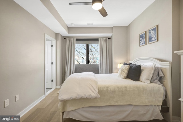 bedroom featuring visible vents, baseboards, light wood-style floors, and ceiling fan