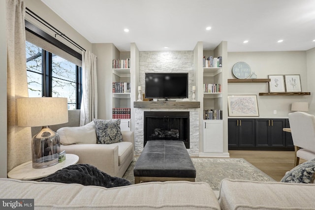 living room with built in features, light wood-type flooring, recessed lighting, and a fireplace