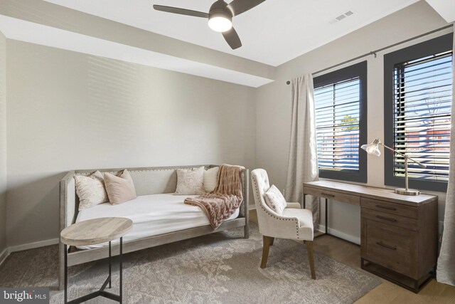 sitting room with a ceiling fan, wood finished floors, baseboards, and visible vents