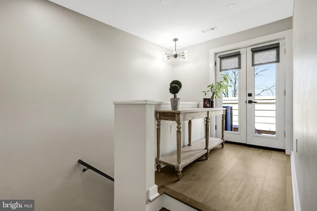 foyer featuring visible vents, a notable chandelier, wood finished floors, french doors, and baseboards